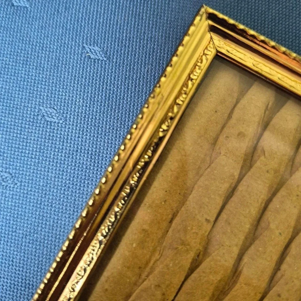 Vintage hinged gold picture frame with vertical ridges.